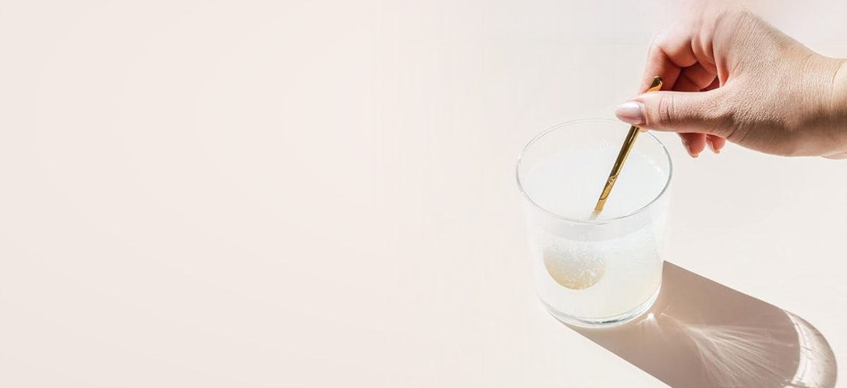 A hand stirring magnesium powder into a glass of water